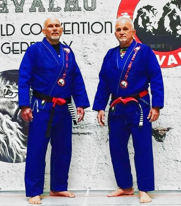 Ricardo Carvalho and Edison Carvalho BJJ-instructors-in-blue-gis-with-red-belts-standing-before-a-Team-Carvalho-banner-at-a-World-Convention-in-Germany